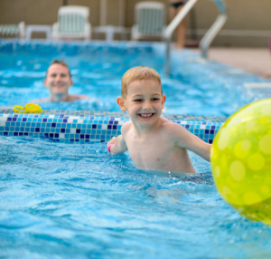 Smiling boy playing with beach ball in pool